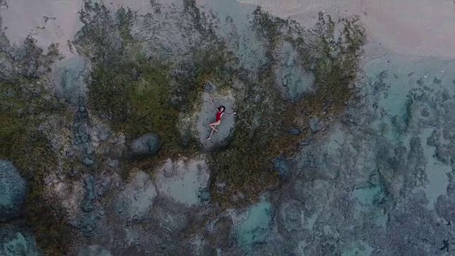 美丽的年轻女子躺在巴厘岛海滩的沙滩上视频素材