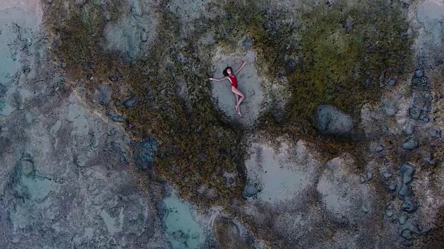 美丽的年轻女子躺在巴厘岛海滩的沙滩上视频素材