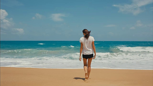 一个女人走在空荡荡的海滩上走向大海视频素材