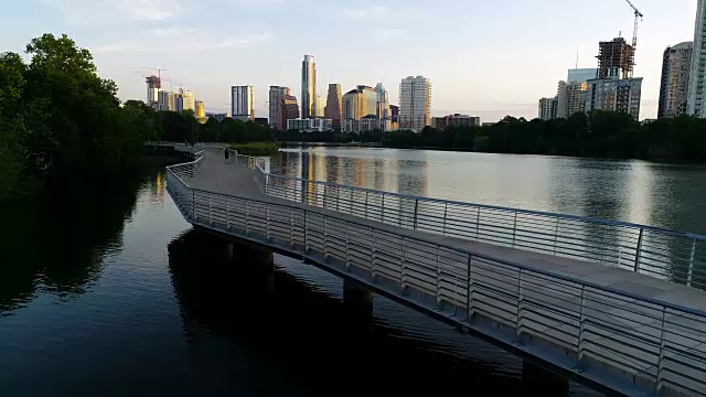 完美的日出天际线城市景观向前移动，在德克萨斯州奥斯汀河畔人行天桥旁边的桥梁倒车视频素材