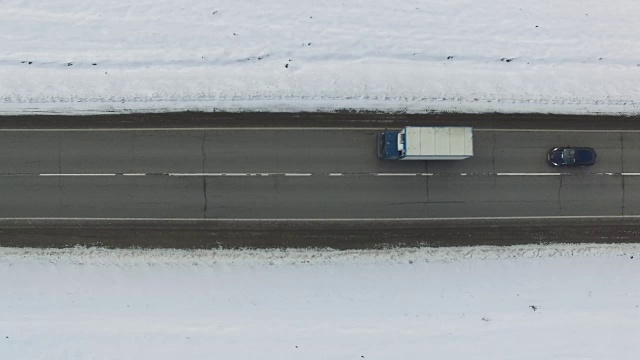 空中垂直拍摄的汽车和卡车在道路上行驶在冬天的一天。无人机向公路移动。视频素材