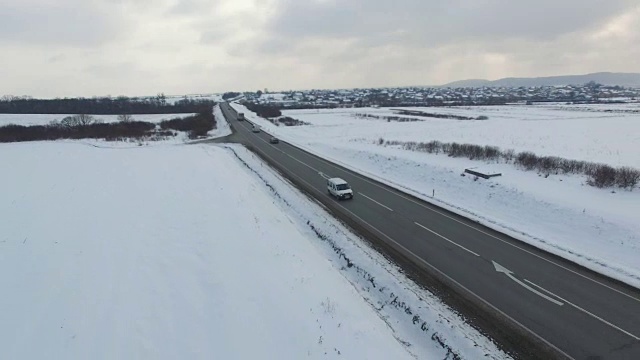 空中拍摄的汽车和卡车在冬季阴天的道路上行驶。视频素材