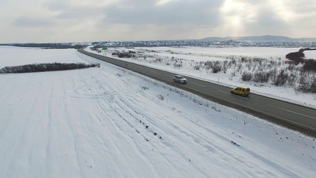 空中拍摄的汽车和卡车在冬季阴天的道路上行驶。视频素材