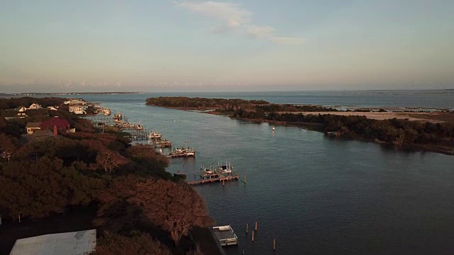 在北卡罗来纳州波弗特，一架无人机在夕阳照耀下的码头和胡萝卜岛上空升起视频素材