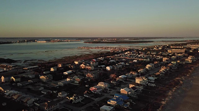 在北卡罗来纳州大西洋海滩，一架无人机在夕阳照耀下的海滨房屋上空盘旋视频素材