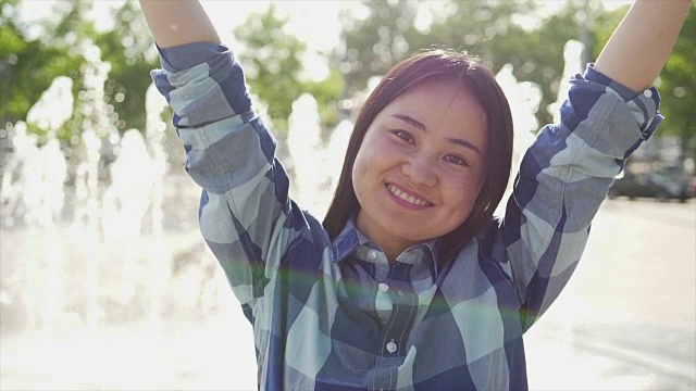 美丽的亚洲女孩在喷泉前跳舞在城市的环境在夏天的一天视频素材