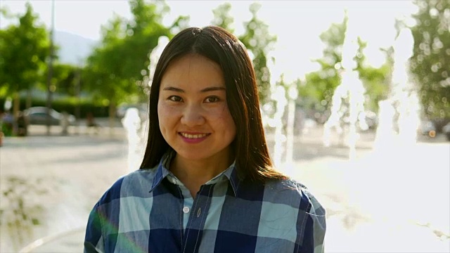 漂亮的亚洲女人在一个温暖的一天在城市的喷水喷泉附近有乐趣视频素材