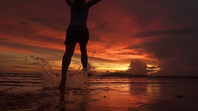 剪影:一个快乐的女人张开双臂奔向美丽的夕阳视频素材