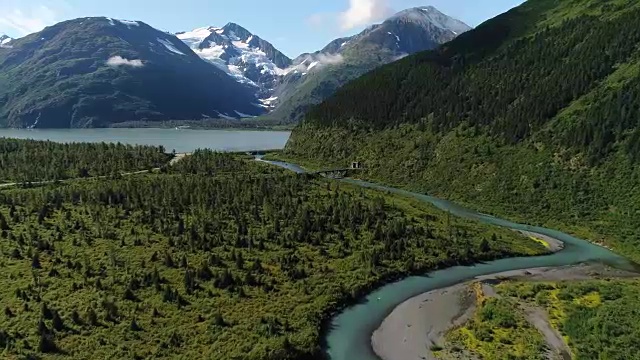 一架无人机飞过一条河流，飞向阿拉斯加波蒂奇森林山区的一个湖泊视频素材