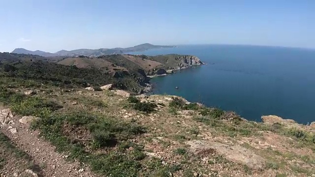 一名身穿裙子的年轻女子走在法国地中海的岩石海岸上视频素材