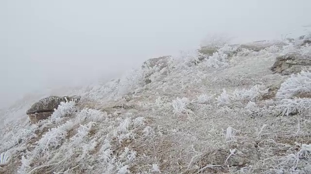 在石质山坡上的运动。岩石和草地上覆盖着白霜视频素材