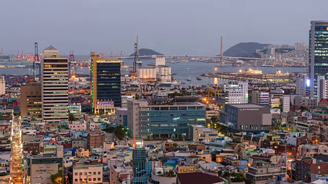 从白天到晚上的城市景观和住宅区以及在远处的釜山的光丹岛视频素材