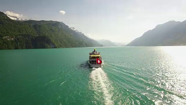 鸟瞰图的旅游船在湖与瑞士国旗在山脉和高山环境视频素材