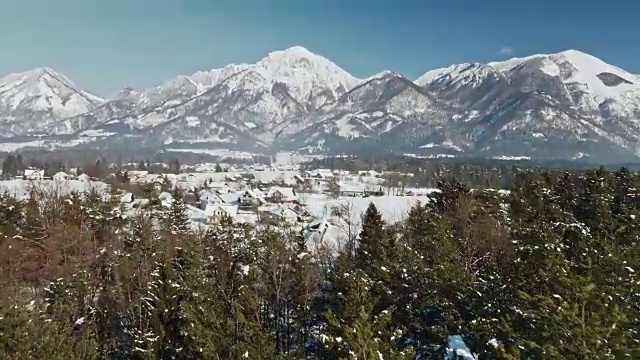 在一个阳光明媚的冬日，鸟瞰山下的雪村视频素材