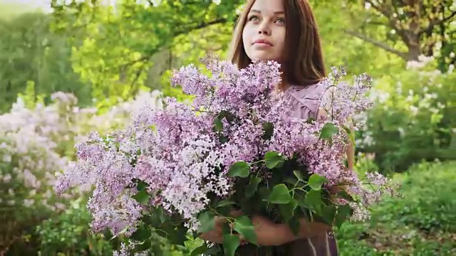 这个年轻女孩享受着丁香花的香味视频素材