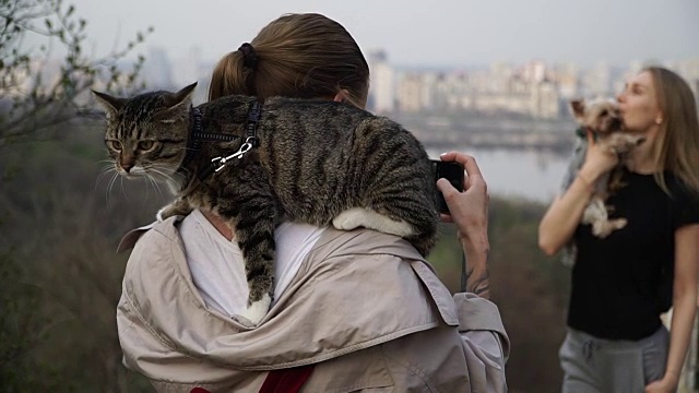 Selfy。一个肩上扛着一只猫的女孩带着一个女孩和一只狗视频素材