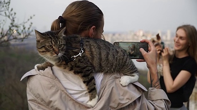 Selfy。一个肩上扛着一只猫的女孩带着一个女孩和一只狗视频素材