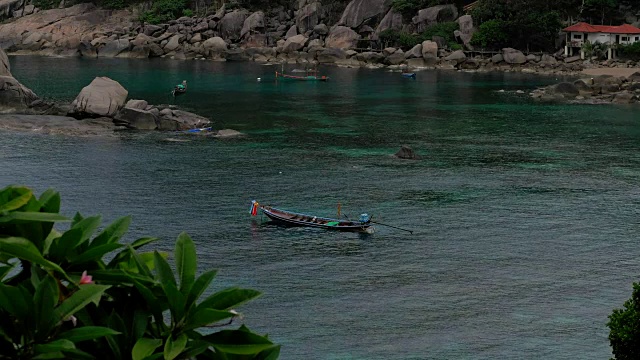 热带海滩。长尾船在海湾中荡漾着平静的海水。背景是巨大的花岗岩。黄昏时分，带着游客乘独木舟返回休息地点。Koh道、泰国视频素材