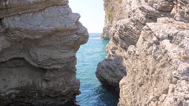 通过岩石狭窄的通道，泻湖碧蓝清澈的大海的景色视频素材