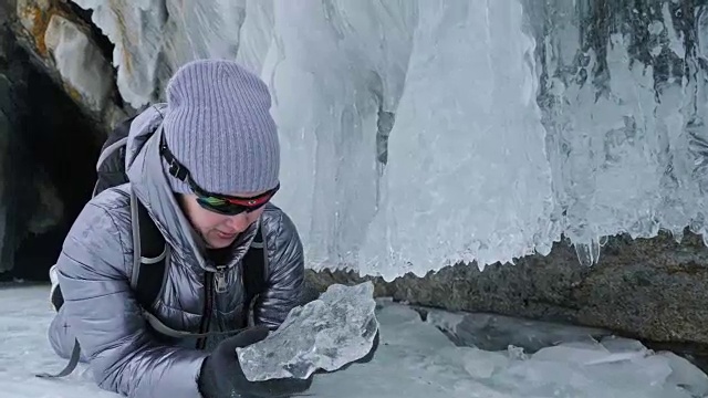 女人在贝加尔湖冰面上的旅行。冬岛之旅。女孩在冰岩石下行走。游客看着美丽的冰洞。极限跋涉和步行。背包客在大自然中休憩。视频素材