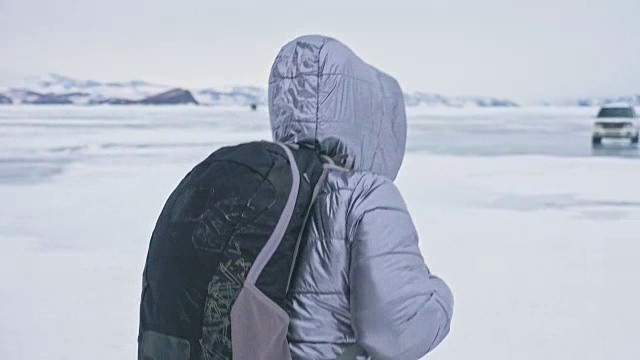 女人在贝加尔湖冰面上的旅行。冬岛之旅。女孩在冰岩石下行走。游客看着美丽的冰洞。极限跋涉和步行。背包客在大自然中休憩。视频素材