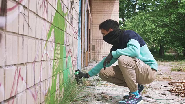 年轻的涂鸦艺术家在墙上，外面作画视频素材