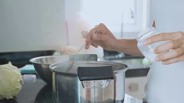 女性在家庭厨房用勺子煮汤，特写。视频素材