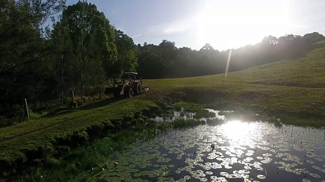 拖拉机在夕阳中驶过睡莲池视频下载