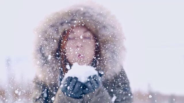 一个女人朝镜头吹雪，慢镜头视频素材