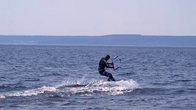 慢镜头:一名男子的风筝滑板沿着一条大河的波浪优美地滑行。水花四溅向不同的方向。阳光明媚的春天。视频素材