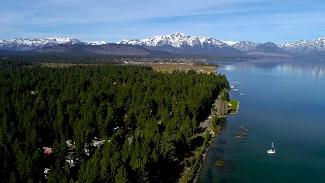 在一个阳光明媚的早晨，一艘帆船停靠在加州塔霍湖的海岸线上，这是一架无人机俯瞰蓝色水域上空的美景视频素材