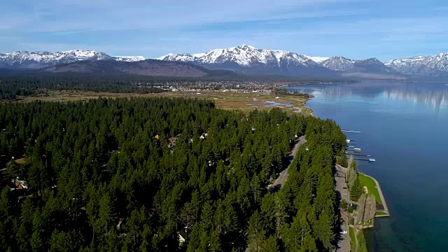 春天的太浩湖，加利福尼亚茂密的森林和葱郁的海湾沿着南岸与雪山景观的背景视频素材