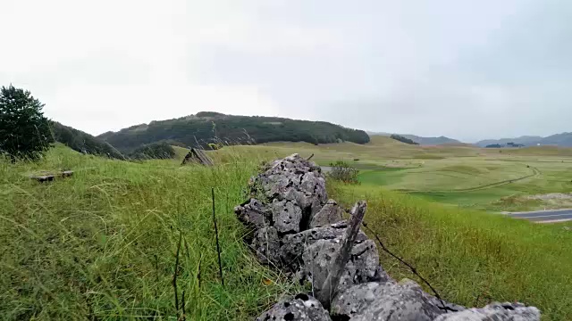 有刺的木板上的柱子和篱笆旁的石头山上废弃的小屋视频素材