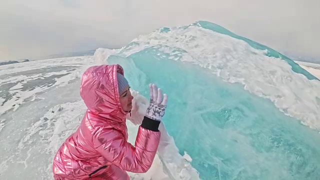 一个女孩走在贝加尔湖破裂的冰面上。一名女旅行者探索并看着一块浮冰。这是自然界中最神奇最纯净的地方。冰环绕着旅行者所有的旅程。视频素材