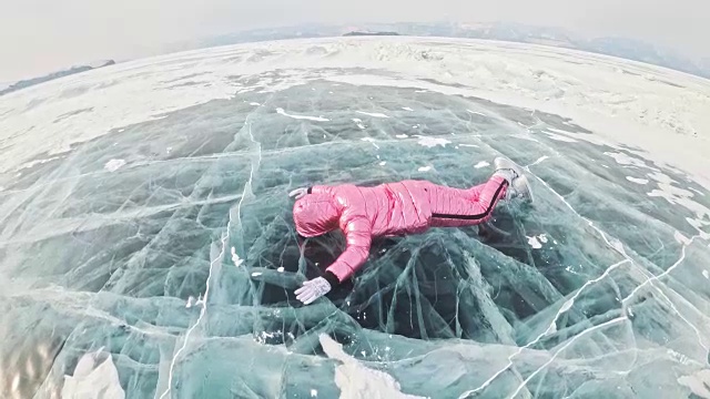 一个女孩走在贝加尔湖破裂的冰面上。一名女旅行者探索并看着一块浮冰。这是自然界中最神奇最纯净的地方。冰环绕着旅行者所有的旅程。视频素材