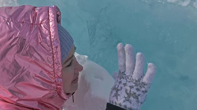 一个女孩走在贝加尔湖破裂的冰面上。一名女旅行者探索并看着一块浮冰。这是自然界中最神奇最纯净的地方。冰环绕着旅行者所有的旅程。视频素材