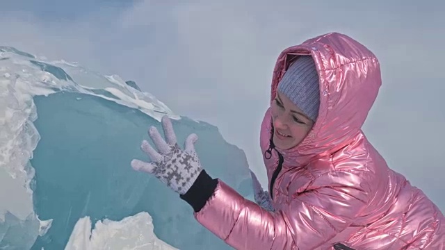 一个女孩走在贝加尔湖破裂的冰面上。一名女旅行者探索并看着一块浮冰。这是自然界中最神奇最纯净的地方。冰环绕着旅行者所有的旅程。视频素材