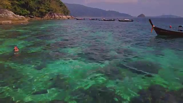 鸟瞰图的热带海滩，长尾船，皮划艇和岩石海岸与水晶清澈的绿松石水Koh Kla, Koh Lipe, Satun，泰国视频素材