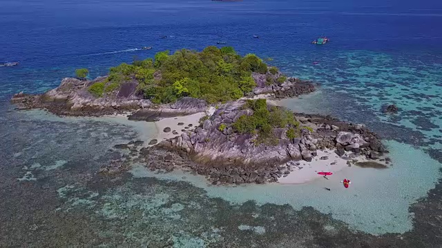 鸟瞰图的热带海滩，长尾船，皮划艇和岩石海岸与水晶清澈的绿松石水Koh Kla, Koh Lipe, Satun，泰国视频素材