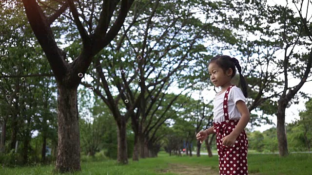 慢镜头，快乐的亚洲女孩，享受在公园里玩泡泡。视频素材