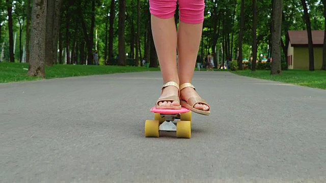 年轻女孩在公园的路上玩滑板视频素材