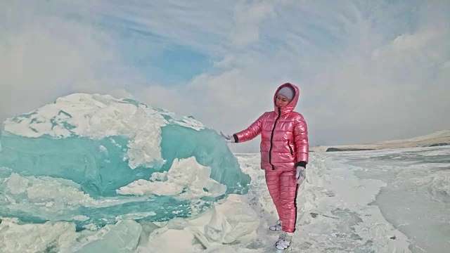 一个女孩走在贝加尔湖破裂的冰面上。一名女旅行者探索并看着一块浮冰。这是自然界中最神奇最纯净的地方。冰环绕着旅行者所有的旅程。视频素材