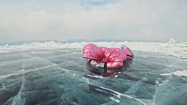 一个女孩走在贝加尔湖破裂的冰面上。一名女旅行者探索并看着一块浮冰。这是自然界中最神奇最纯净的地方。冰环绕着旅行者所有的旅程。视频素材