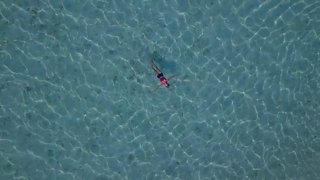 鸟瞰图，一个迷人的女人漂浮在水晶清澈的大海，泰国，萨顿视频素材