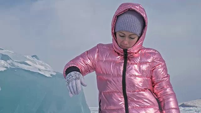 一个女孩走在贝加尔湖破裂的冰面上。一名女旅行者探索并看着一块浮冰。这是自然界中最神奇最纯净的地方。冰环绕着旅行者所有的旅程。视频素材