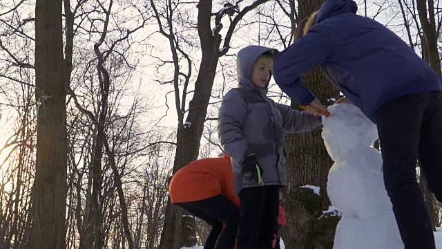 孩子们在冬季公园堆雪人视频素材