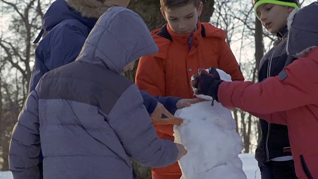 五个男孩在冬季公园堆雪人视频素材