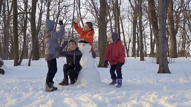 好玩的孩子们在冬季公园的雪人附近互相击掌视频素材