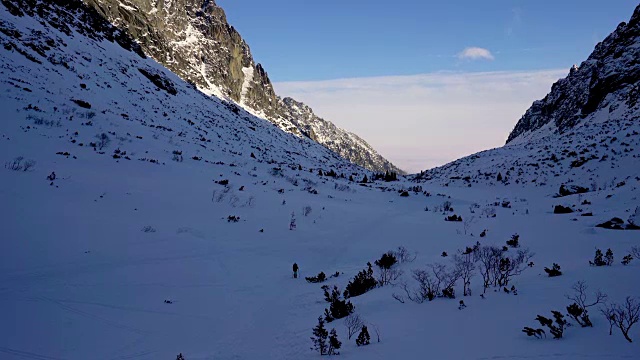 冬天，在寒冷的天气里，在阳光明媚的日子里，在覆盖着积雪的岩石山中徒步旅行视频素材