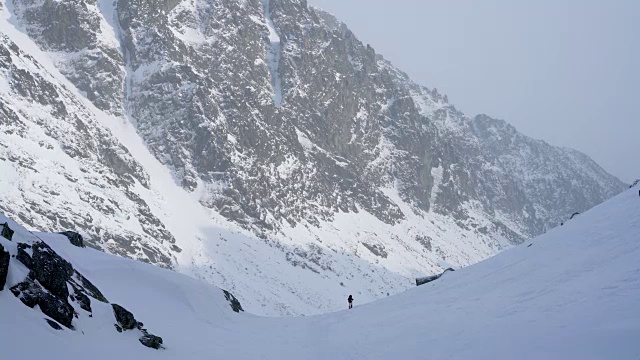 冬天，在寒冷的天气里，在阳光明媚的日子里，在覆盖着积雪的岩石山中徒步旅行视频素材